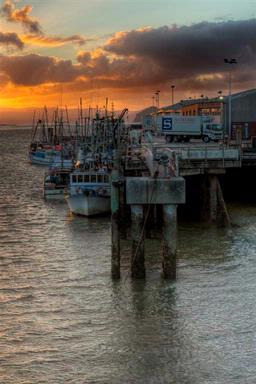 The sun sets over a fleet of fishing boats moored at the Onehunga Wharf.